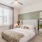 Bedroom in an apartment furnished with a queen-size bed, two nightstands, carpet flooring, wide windows, and high ceiling