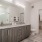 Bathroom of an apartment with vinyl flooring, a high ceiling, a vanity, a wide mirror, excellent lighting, and a walk-in closet 