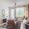 Living room area of an apartment, furnished with a sofa, coffee table, vinyl flooring, and high ceiling