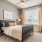 Bedroom in an apartment furnished with a queen-size bed, two nightstands, carpet flooring, wide windows, and high ceiling