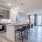 Kitchen area of an apartment fitted with a kitchen island, seating, stainless steel appliances, spacious cabinets, and vinyl flooring at Lyra by Radius